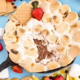 angle view of layers of smores dip with strawberries and graham crackers