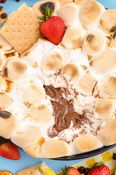 angle view of layers of smores dip with strawberries and graham crackers