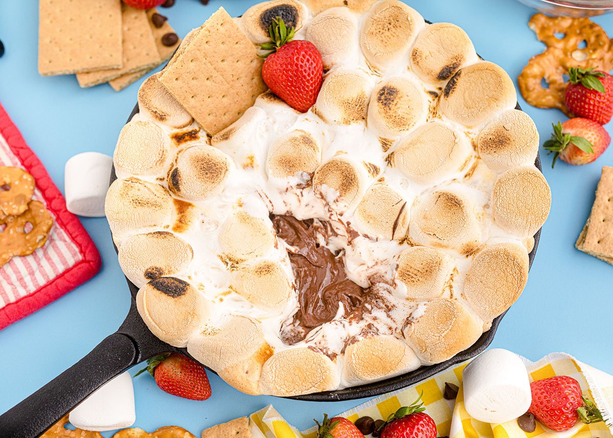 angle view of layers of smores dip with strawberries and graham crackers