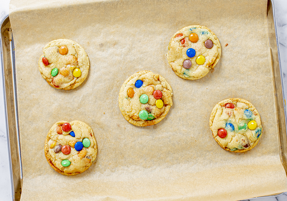overhead shot of baked soft m&m cookies on sheet pan