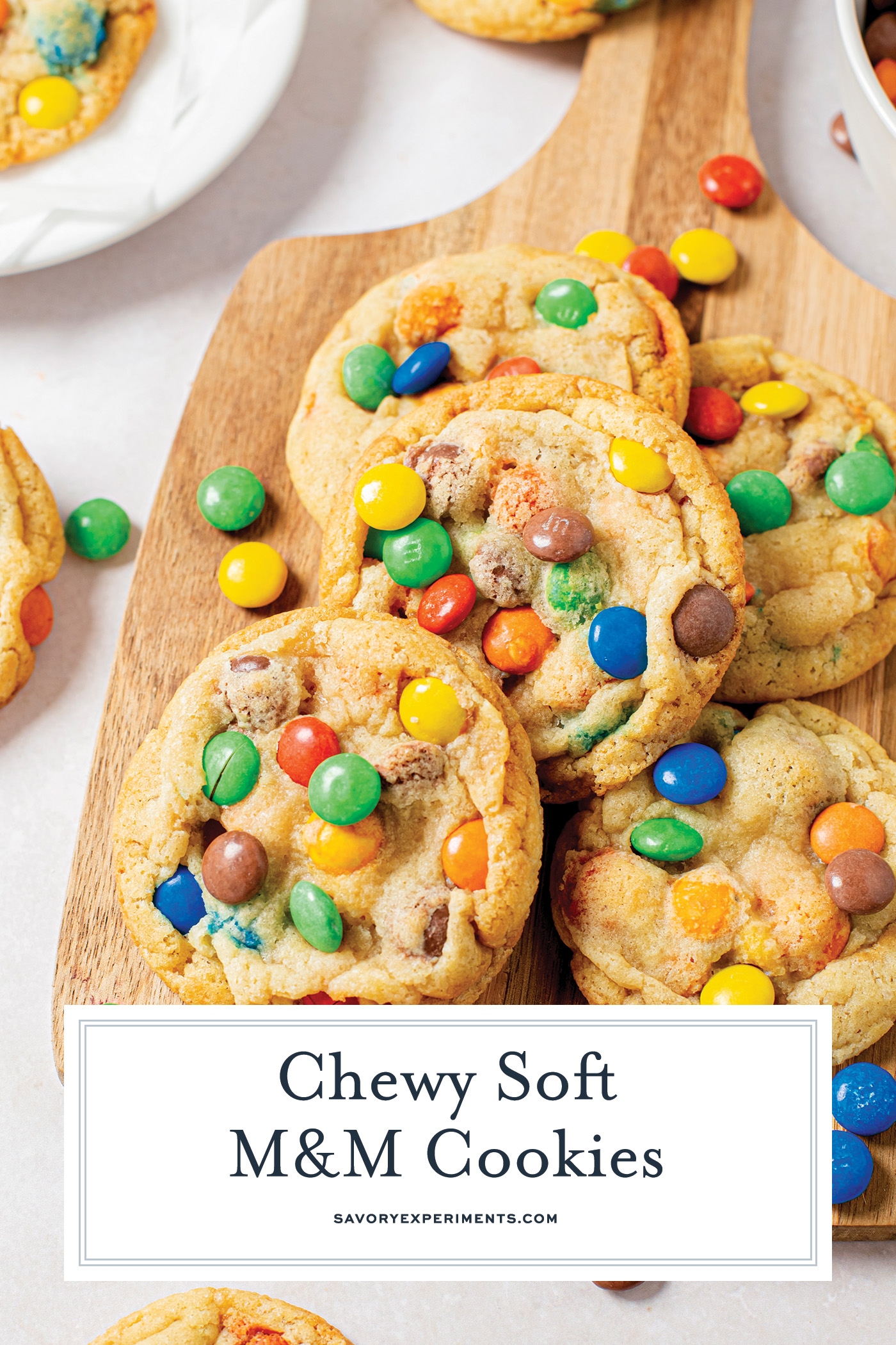 angled shot of soft M&M cookies on a board with text overlay for pinterest