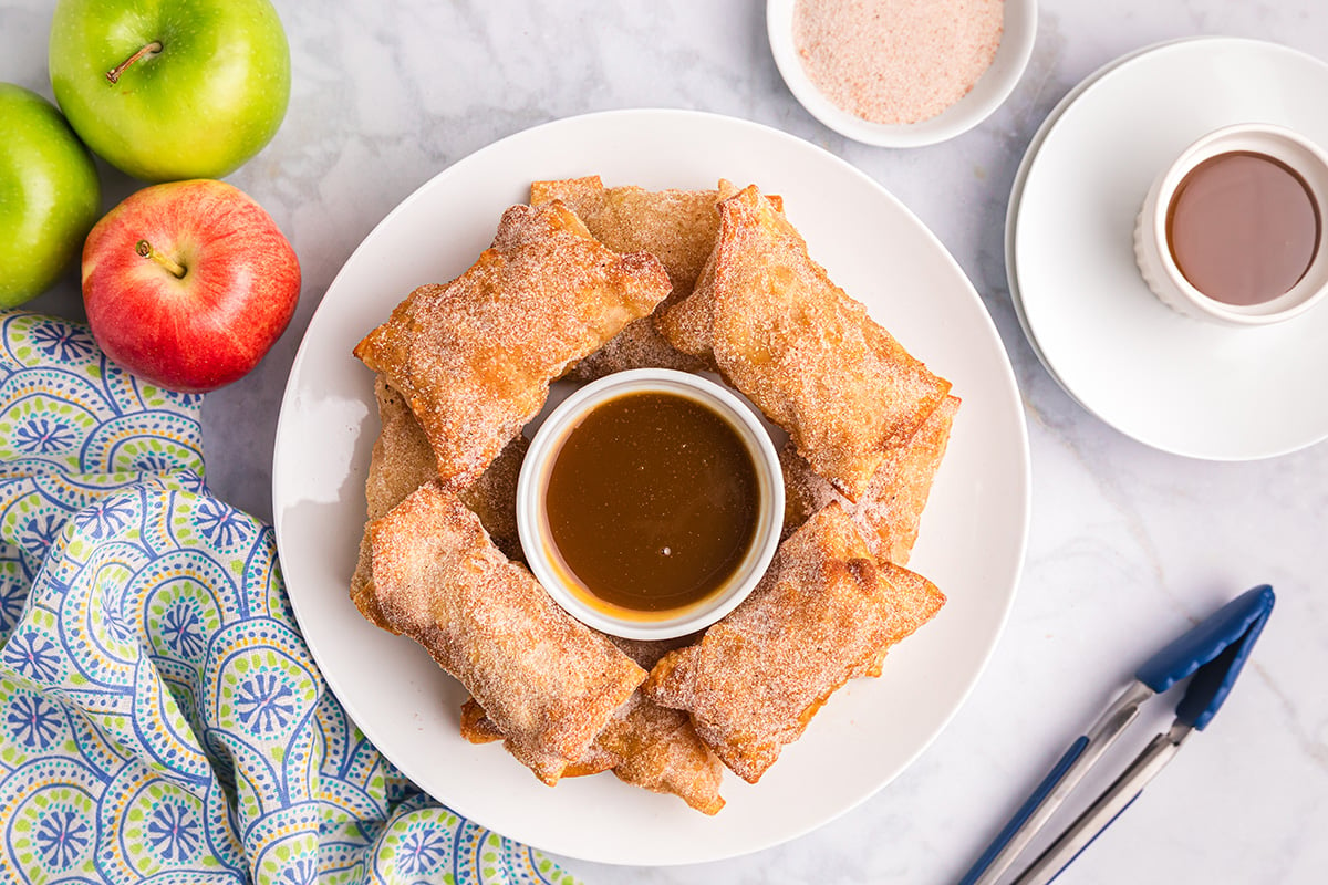overhead shot of apple pie egg rolls on plate with caramel