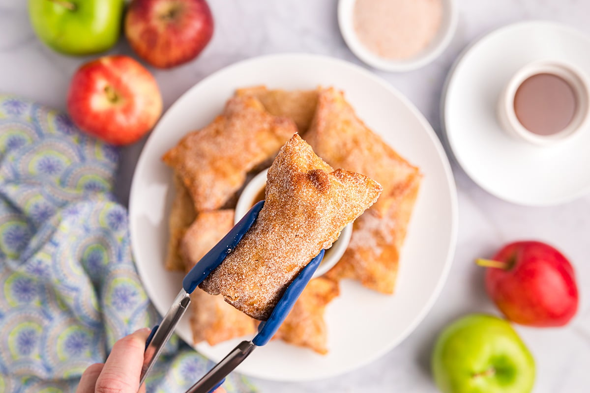 overhead shot of tongs holding apple pie egg roll