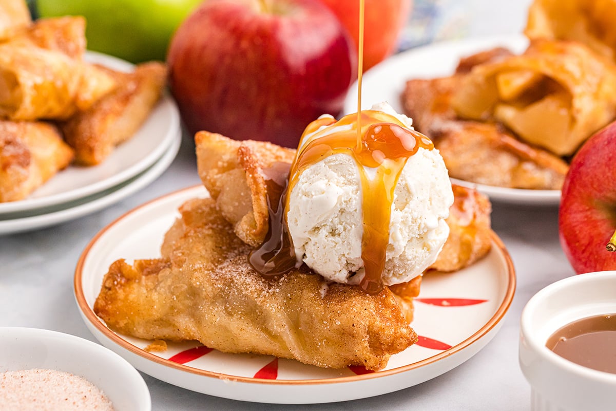 close up of caramel sauce poured onto ice cream and apple pie egg rolls