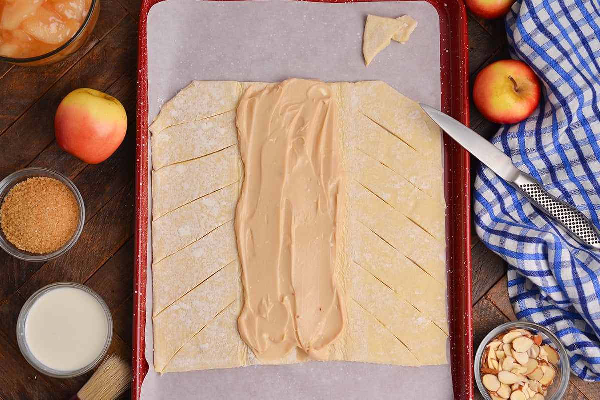 overhead shot of cream cheese spread onto sliced puff pastry