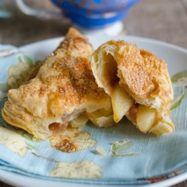angled shot of apple turnover cut in half on plate