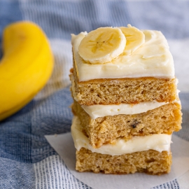 stack of frosted banana blondies with fresh banana slices on top