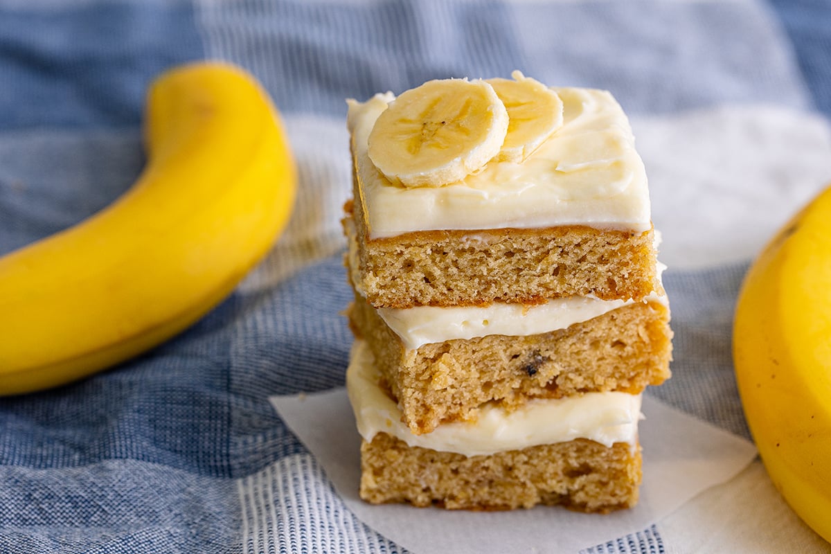 stack of frosted banana blondies with fresh banana slices on top