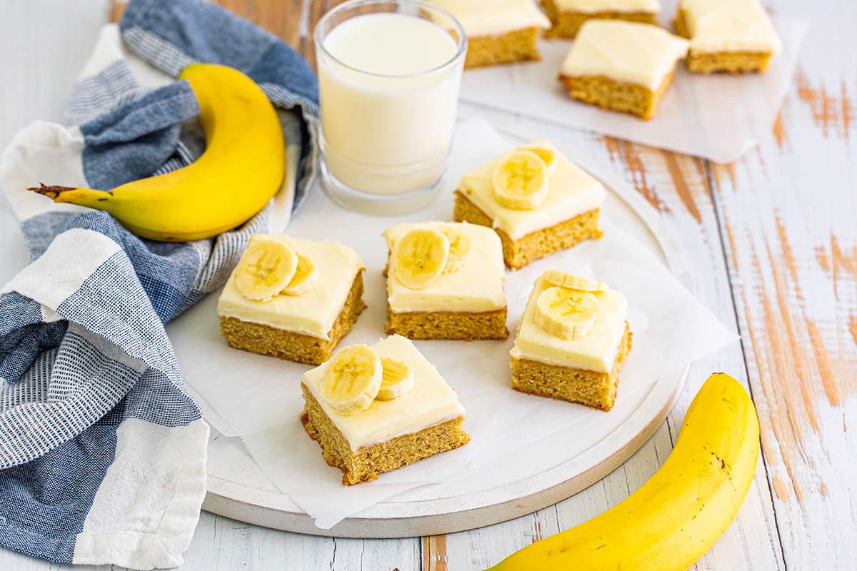 serving platter of frosted blondies with fresh banana and milk