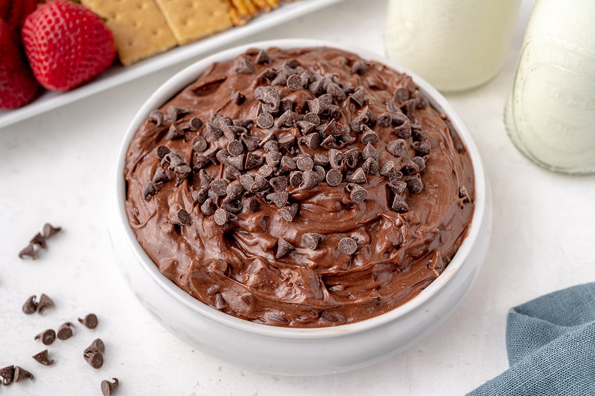angle shot of a white bowl with swirled brownie batter dip and chocolate chips