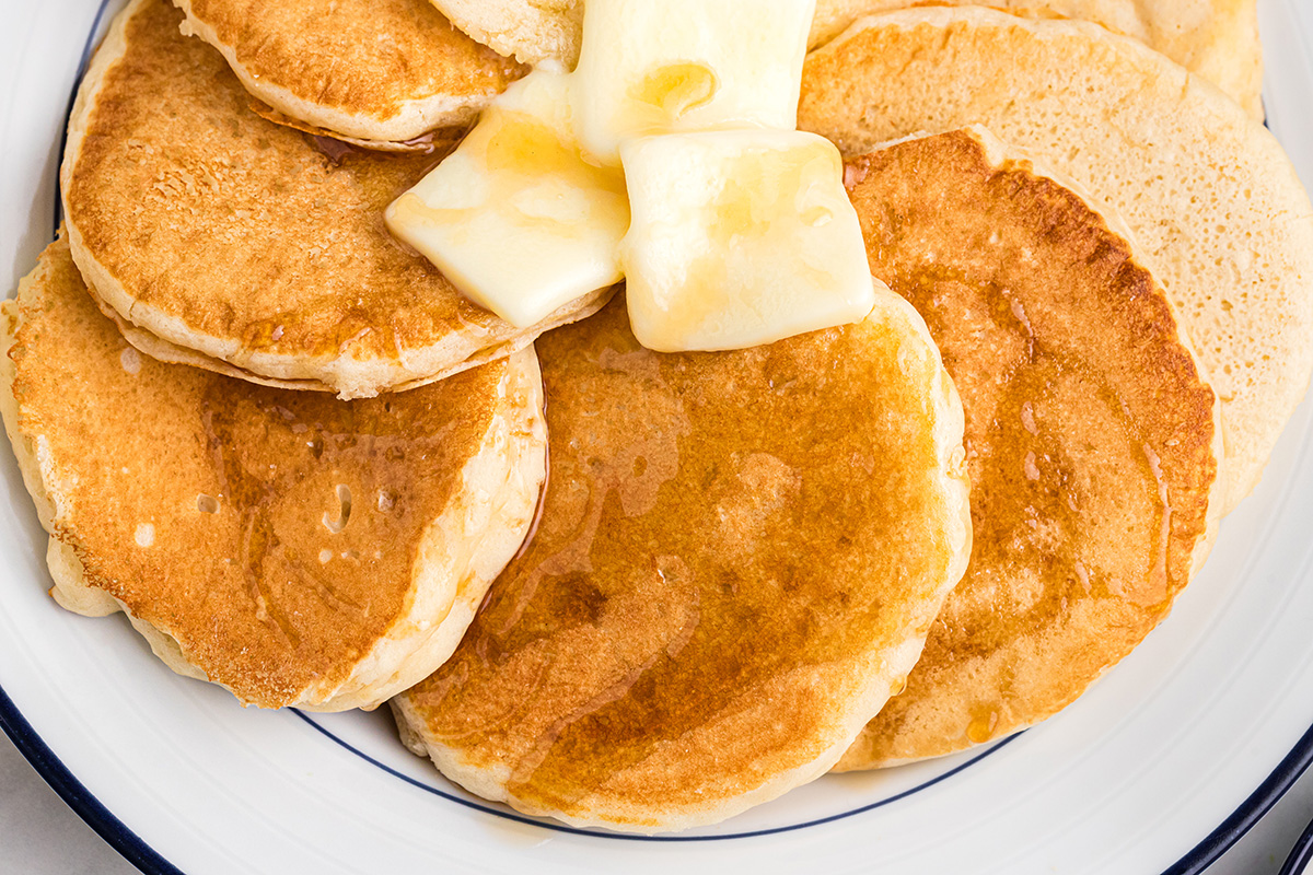 overhead shot of butter and syrup on plate of buttermilk pancakes