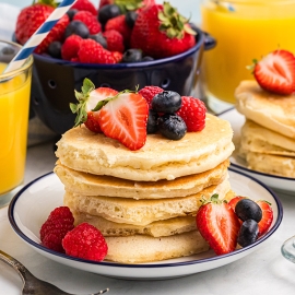 stack of pancakes on plate topped with fruit