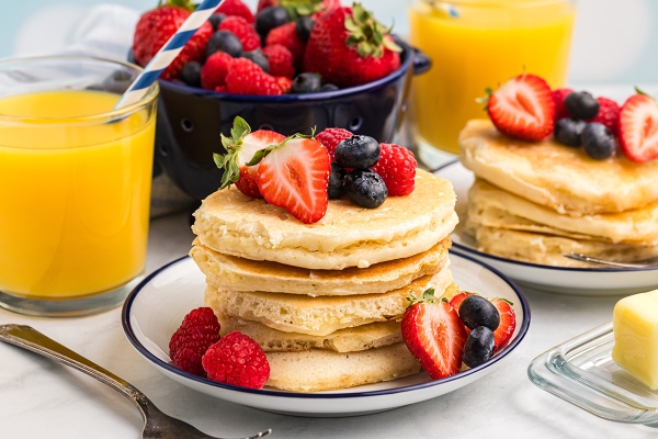 stack of pancakes on plate topped with fruit