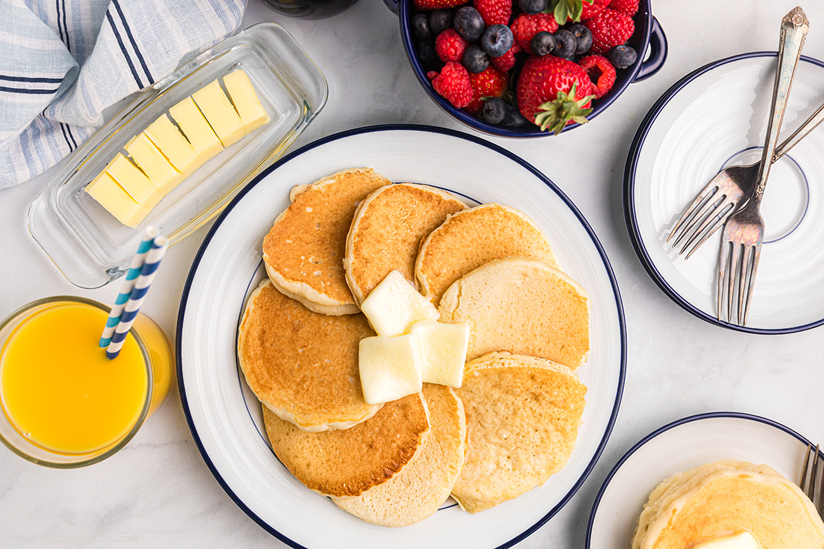 overhead shot of plate of pancakes topped with butter