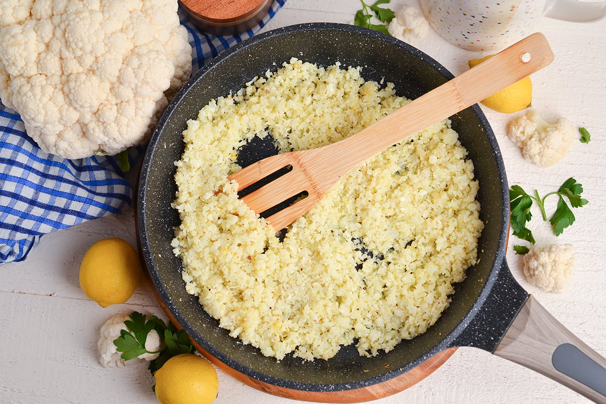 overhead shot of wooden spoon in skillet of cauliflower rice