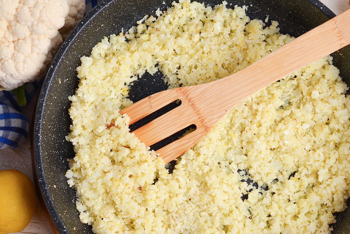 close up overhead shot of wooden spoon in skillet of cauliflower rice
