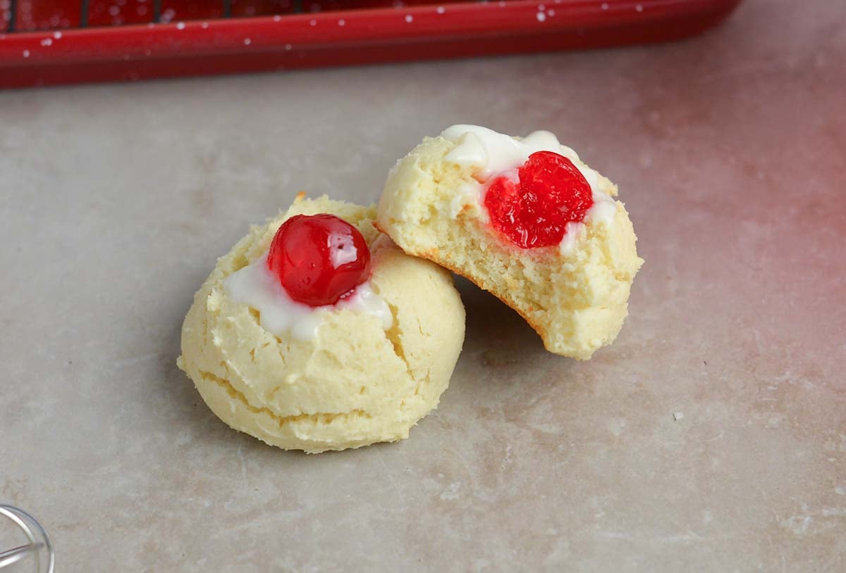 two cookies with cherries, one with half a bite taken out