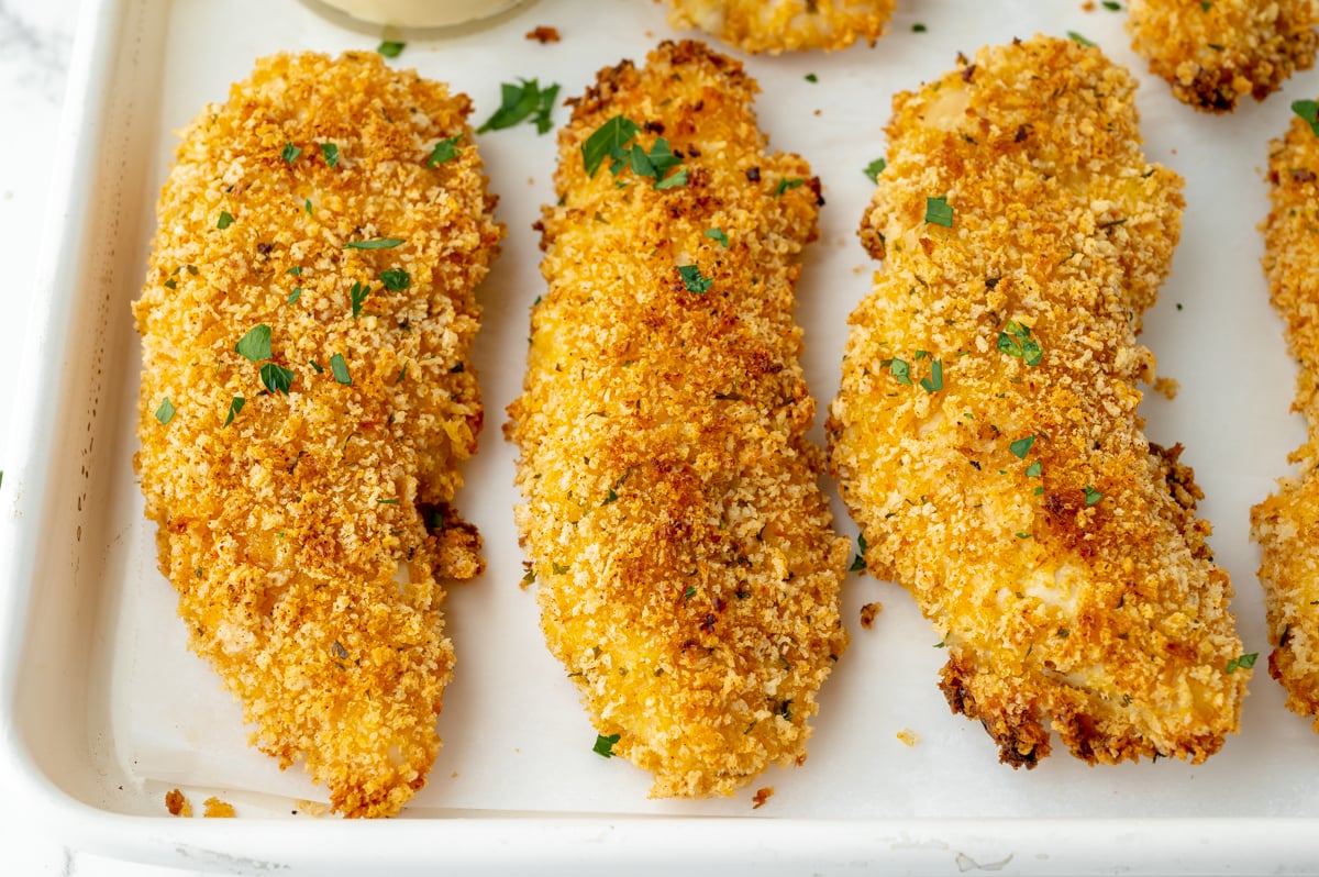 angled shot of crispy baked chicken tenders on sheet pan