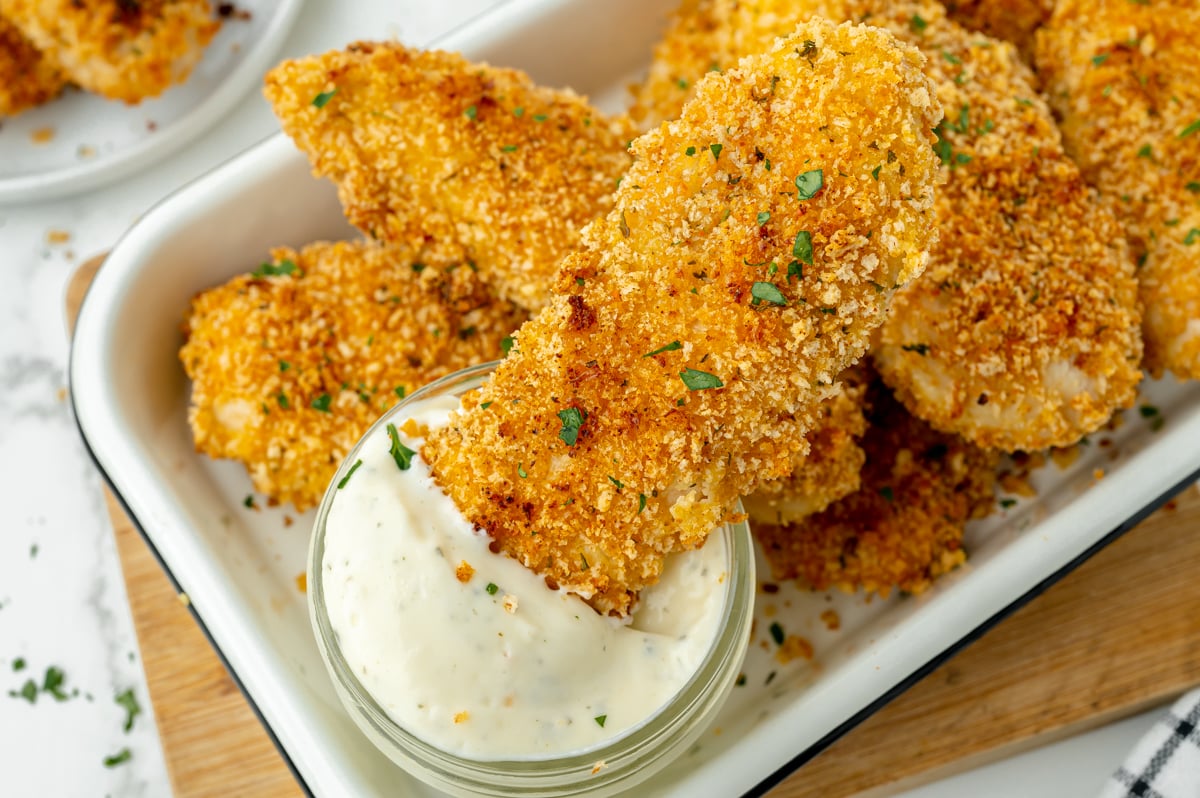 angled shot of crispy baked chicken tender dipped in ranch
