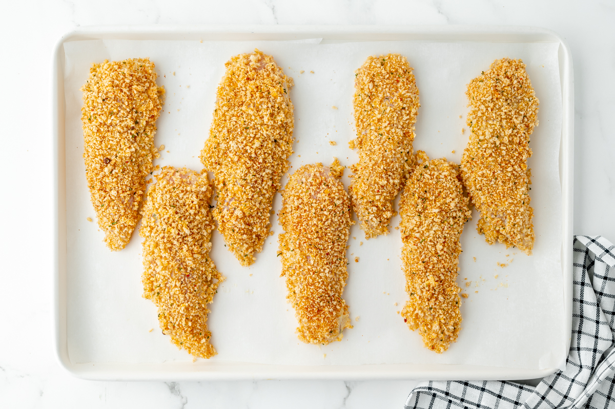 overhead shot of coated chicken tenders on sheet pan