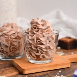 head-on shot of two glass jars with piped whipped cream