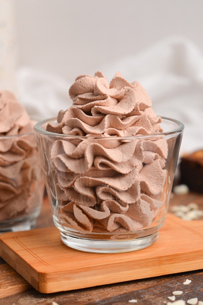 head-on shot of two glass jars with piped whipped cream