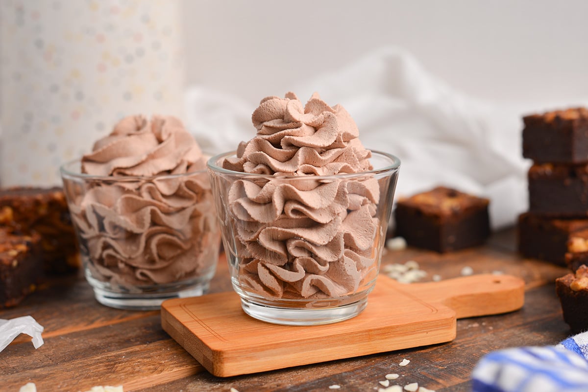 head-on shot of two glass jars with piped whipped cream