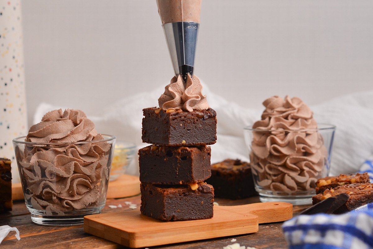 piping bag putting whipped cream on brownies