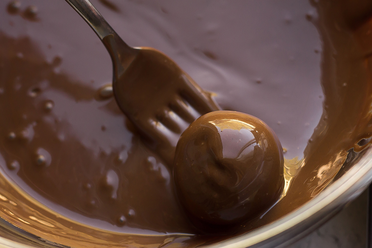 dipping a truffle in melted chocolate