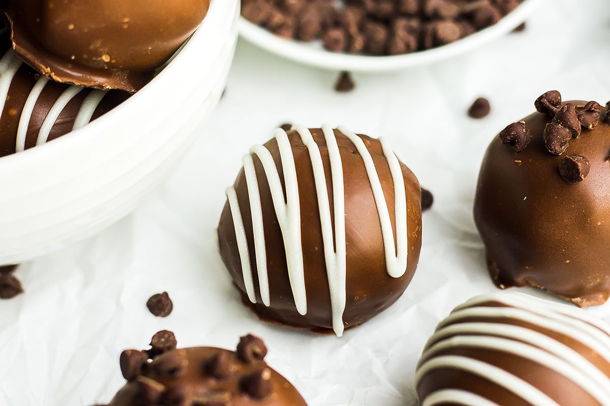 close up of a white chocolate drizzled cookie dough truffle