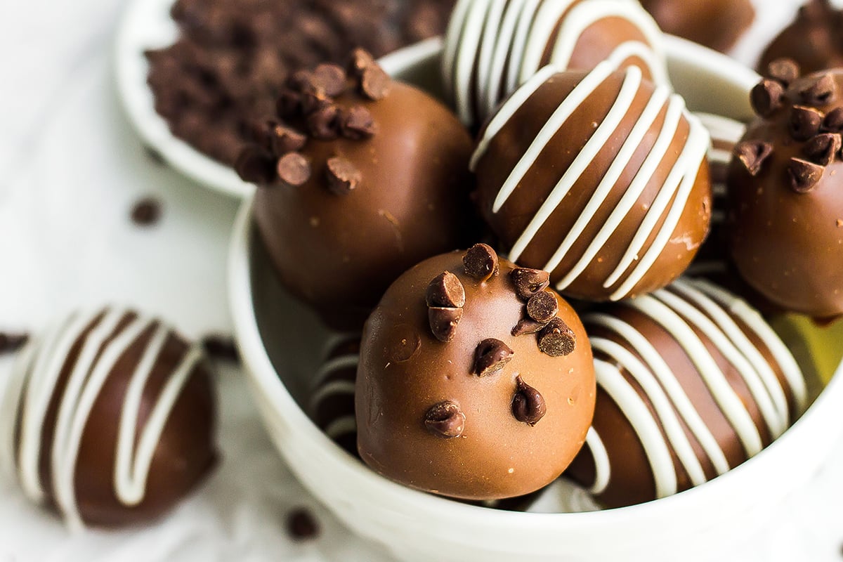 bowl of cookie dough truffles with mini chocolate chips and white chocolate drizzles