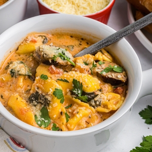 close up angled shot of spoon in bowl of tortellini and sausage soup