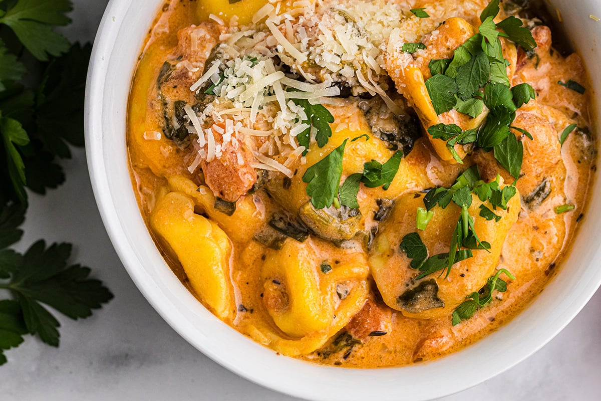 close up overhead shot of tortellini and sausage soup in bowl