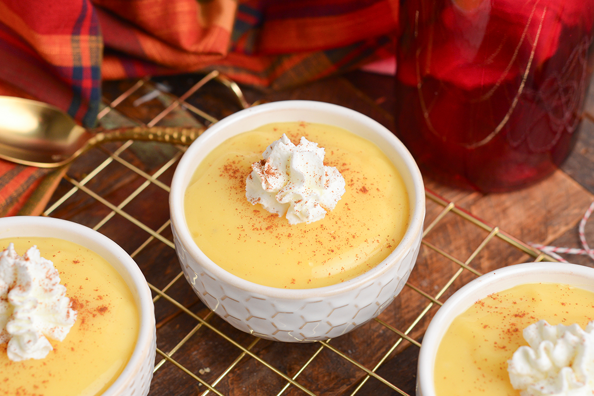 close up angled shot of eggnog pudding in cup with whipped cream