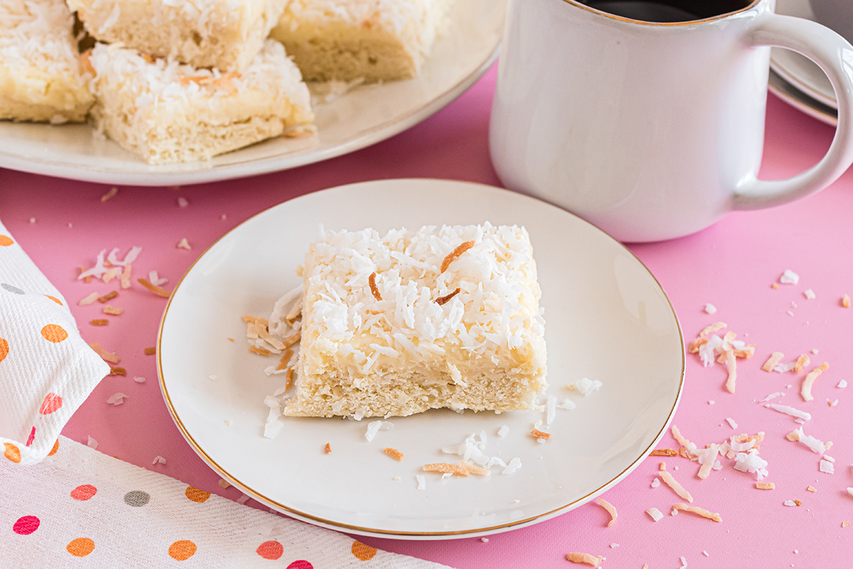 coconut bar on a white serving plate with a cup of coffee