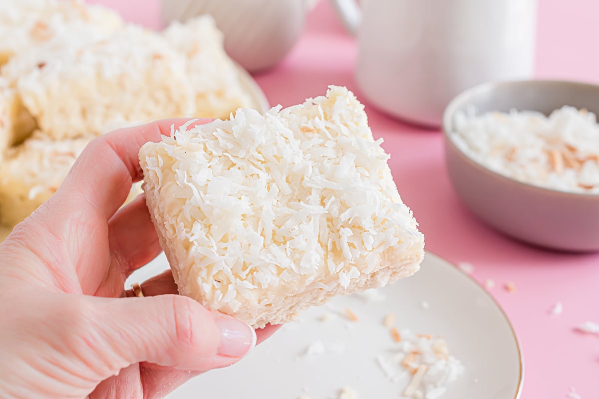 hand holding a frosted coconut bar cookie 