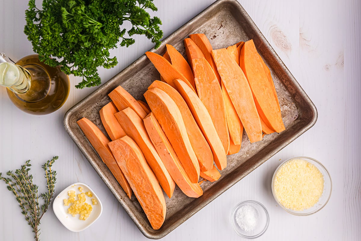 overhead shot of raw sweet potato wedges on sheet pan