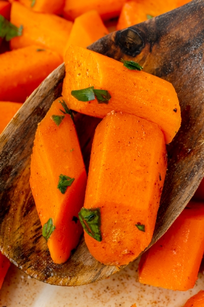 close up shot of honey glazed carrots on wooden spoon