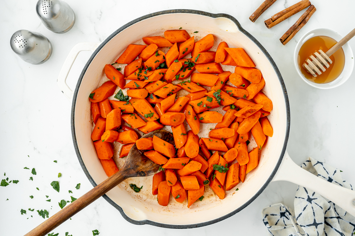 overhead shot of wooden spoon in pan of honey glazed carrots