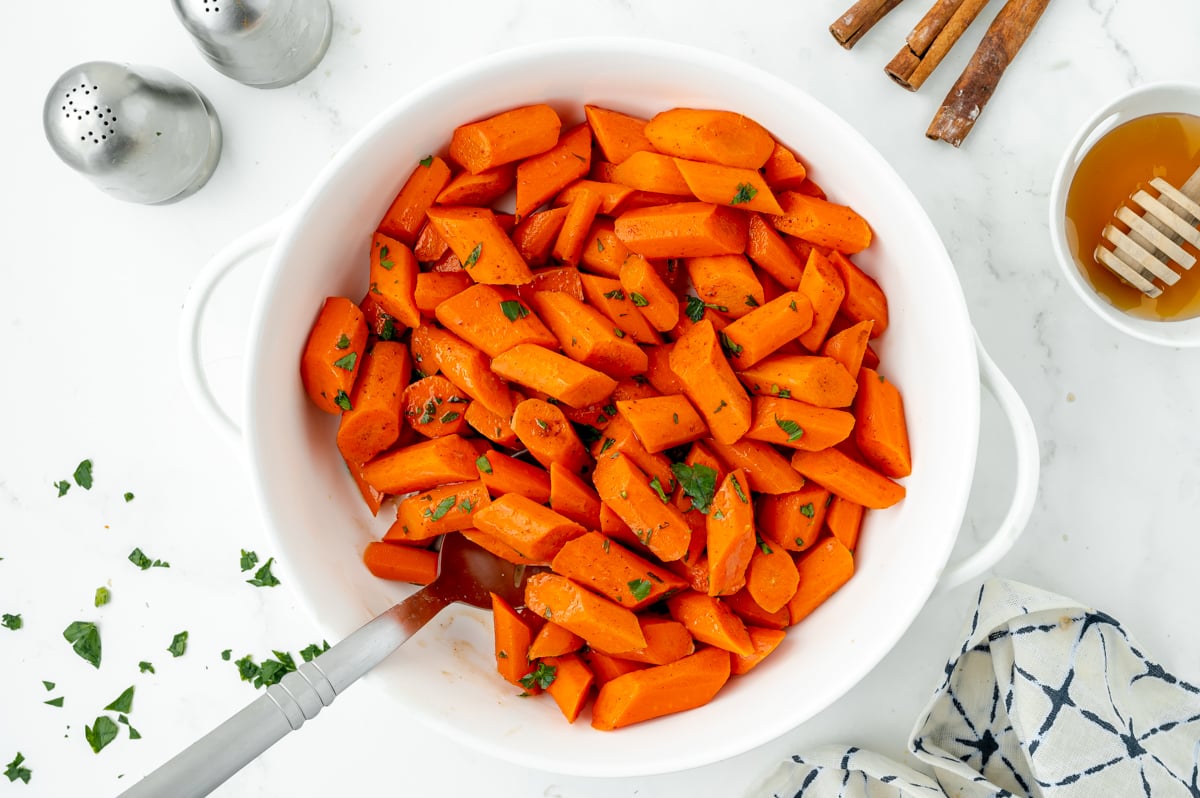 overhead shot of honey glazed carrots in bowl with serving spoon