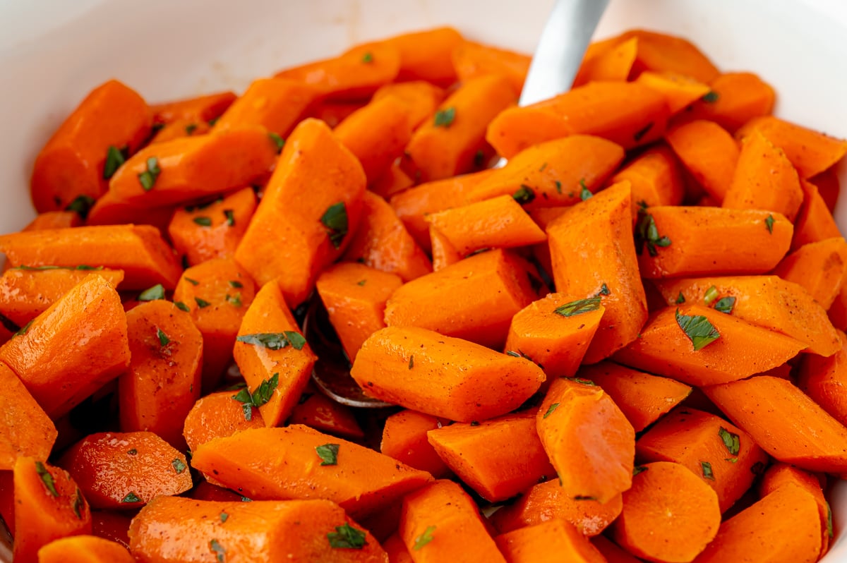 angled shot of serving spoon in bowl of honey glazed carrots