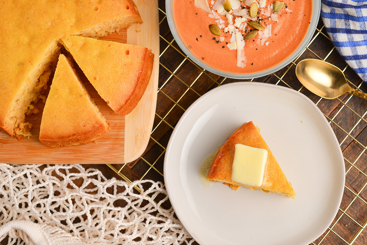 overhead shot of slice of instant pot cornbread on plate and sliced cornbread on cutting board