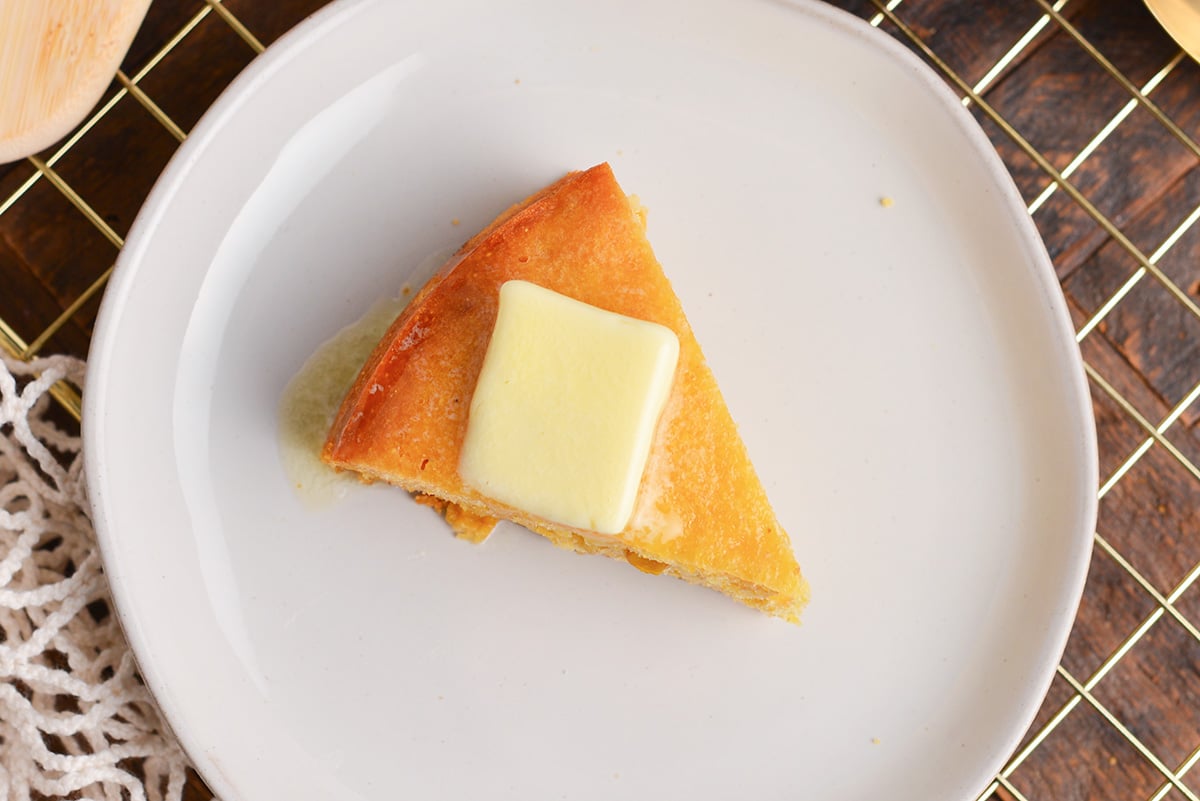overhead shot of slice of cornbread on plate topped with butter