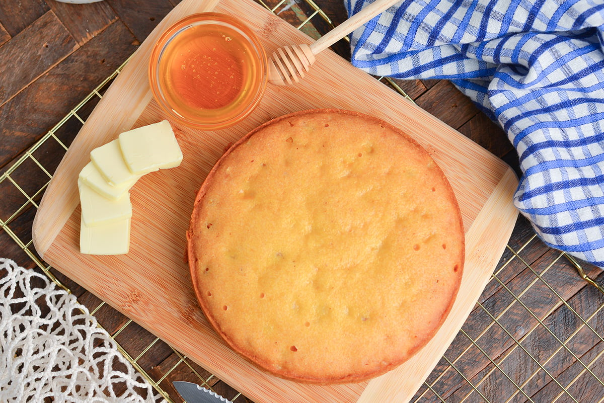overhead shot of instant pot cornbread on cutting board with butter and honey