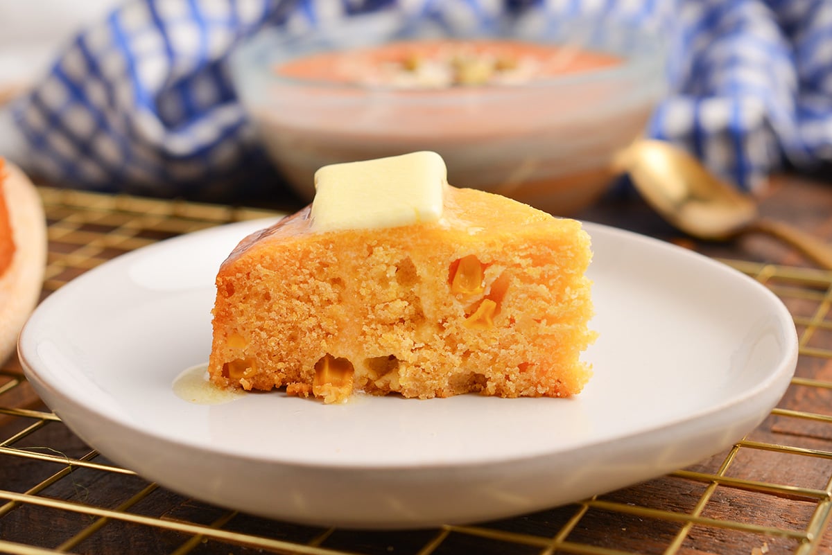 straight on shot of slice of instant pot cornbread topped with butter on plate