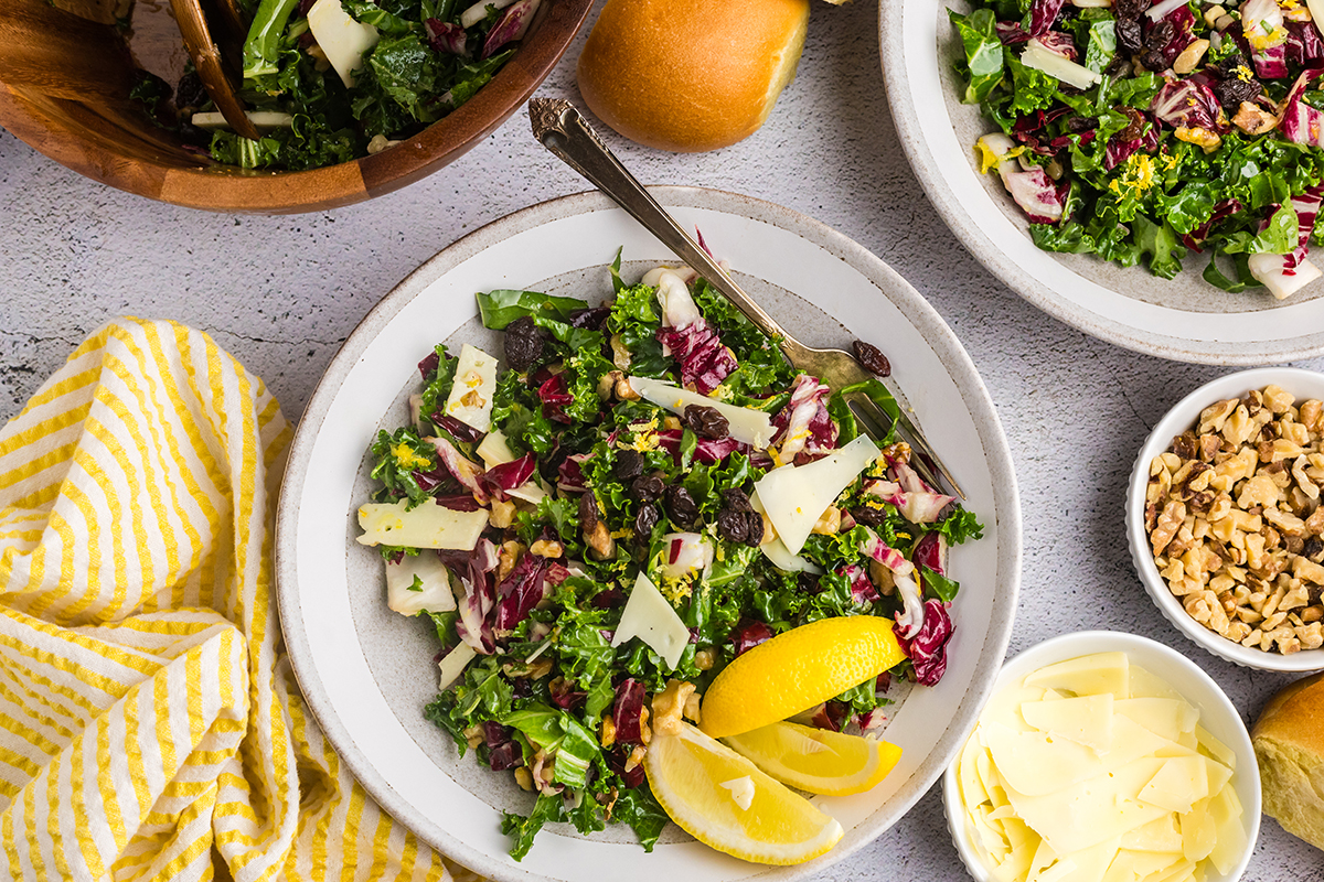 overhead shot of kale salad on plate with fork and lemon wedges