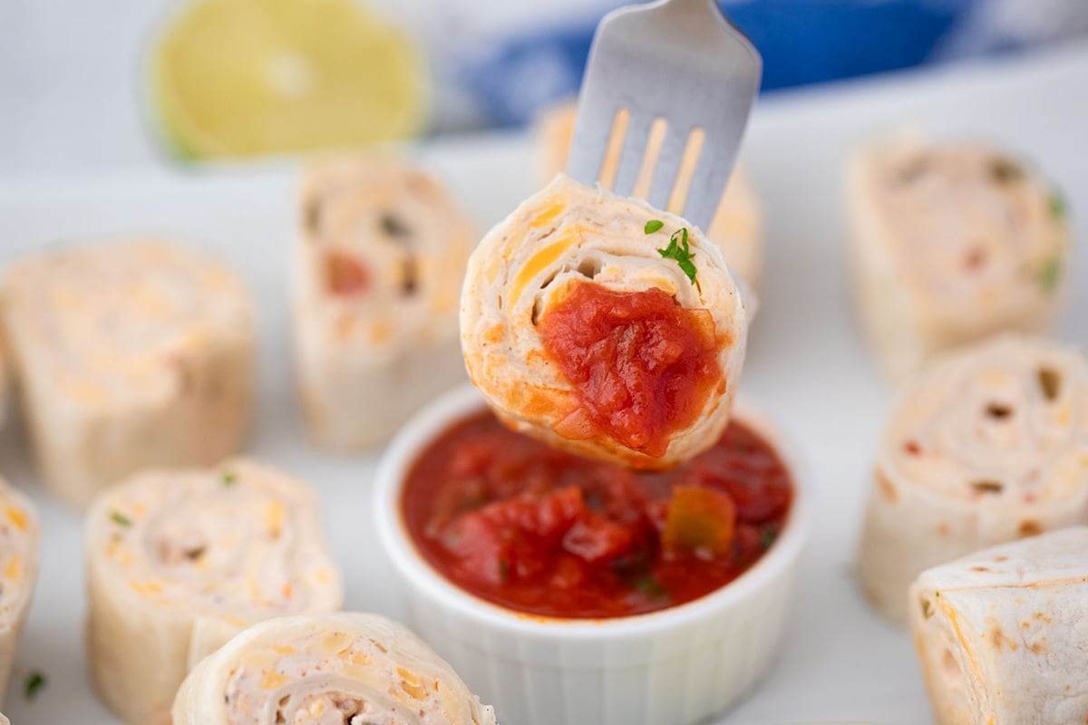 fork dipping mexican pinwheels into bowl of salsa