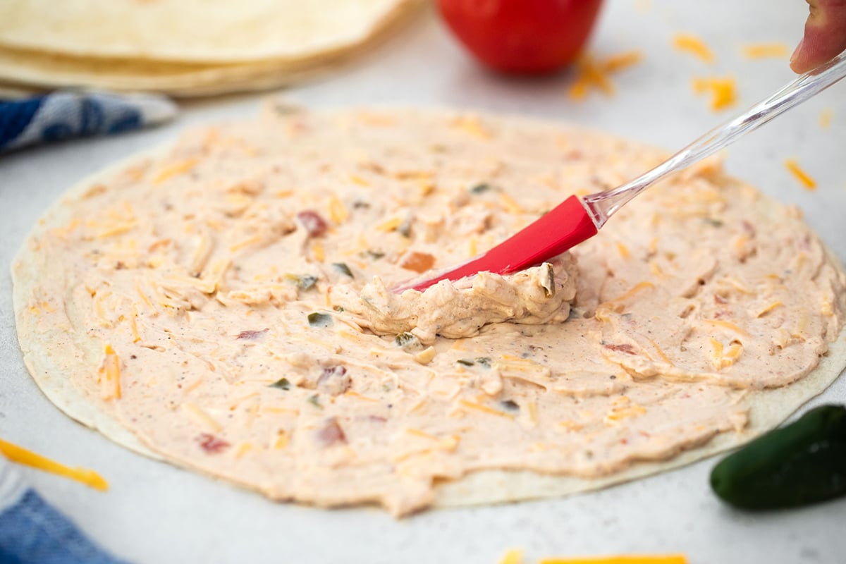 spatula adding cream cheese spread to tortilla