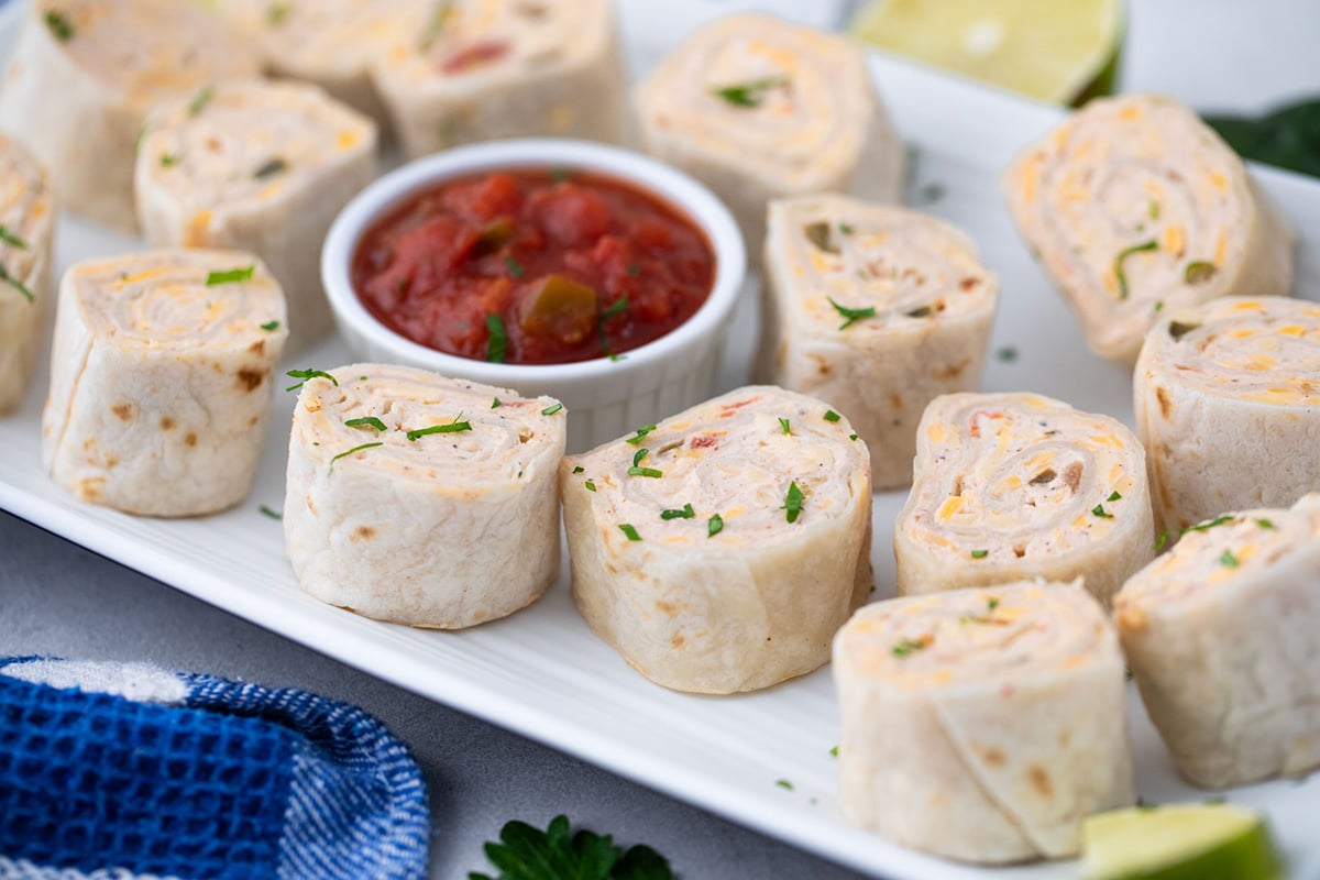 angled shot of mexican pinwheels on a tray with salsa