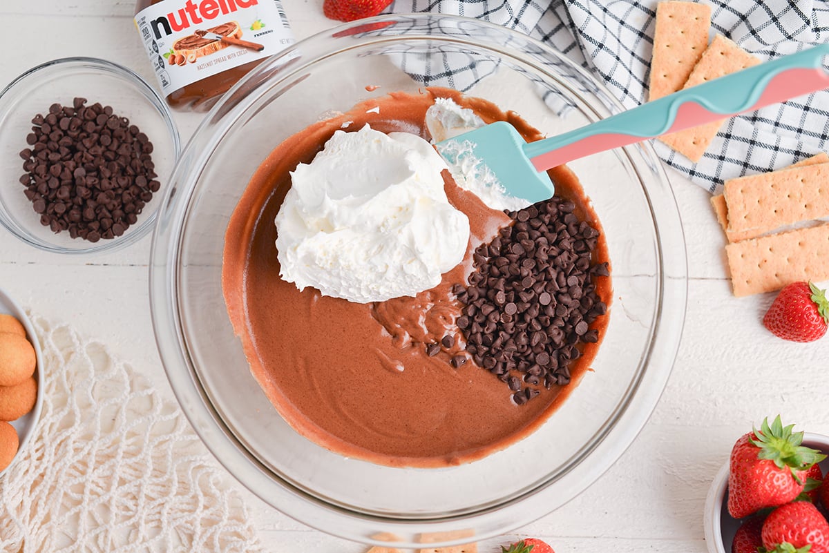 whipped cream and chocolate chips added to bowl of chocolate dip